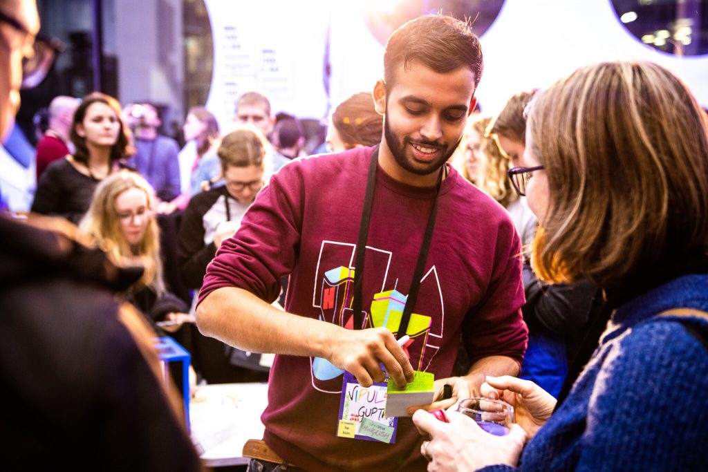 Man demonstrating an activity to a visitor at a busy event