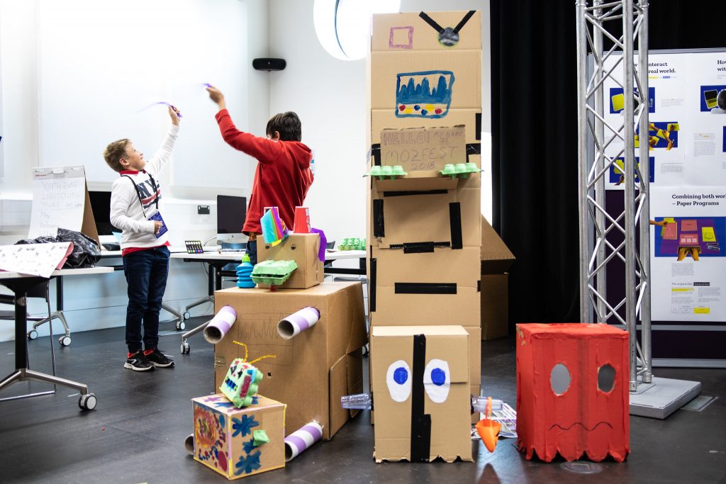 Two people playing with a homemade cardboard arcade game