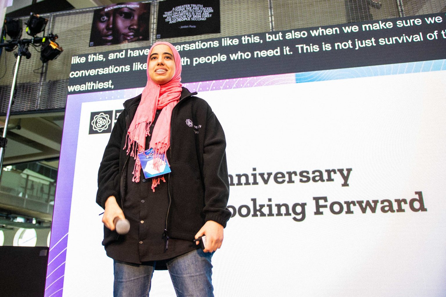 Woman in a red headscarf speaking on stage