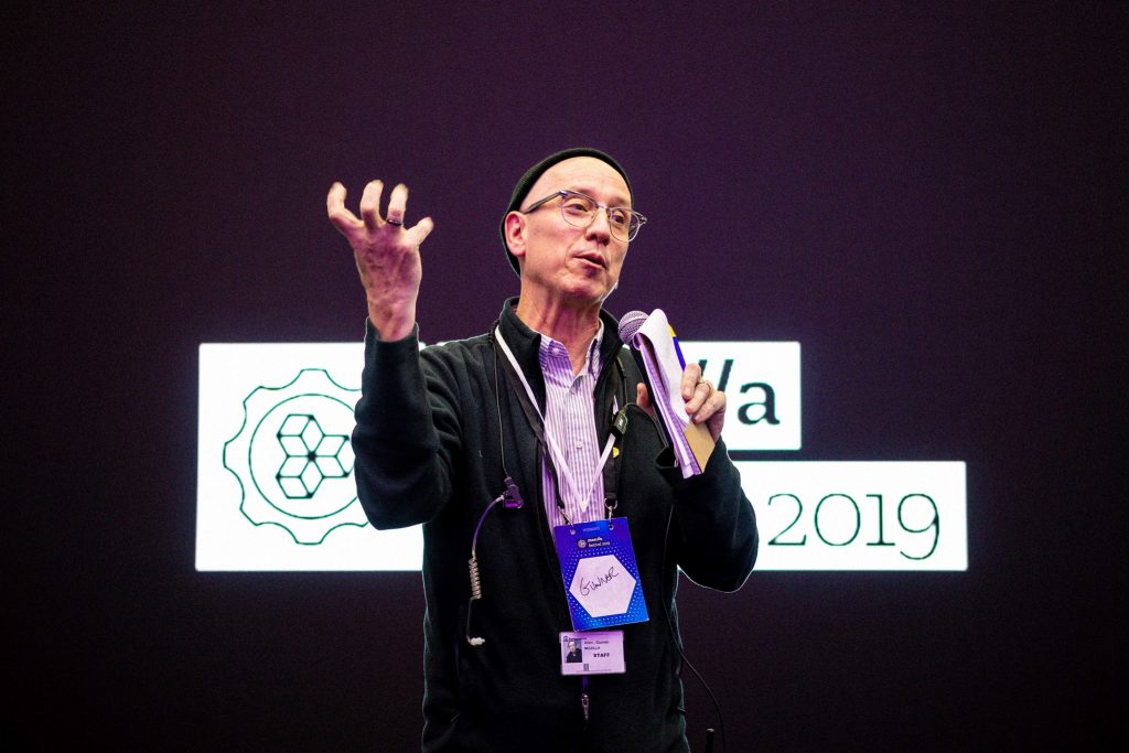 Man gesturing while speaking on a conference stage