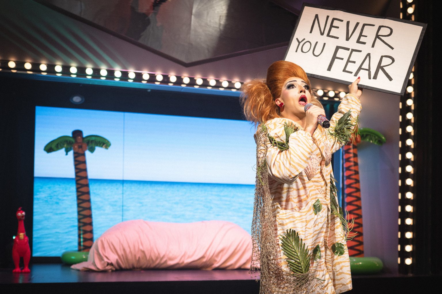 Theatre performer holding a Never You Fear sign