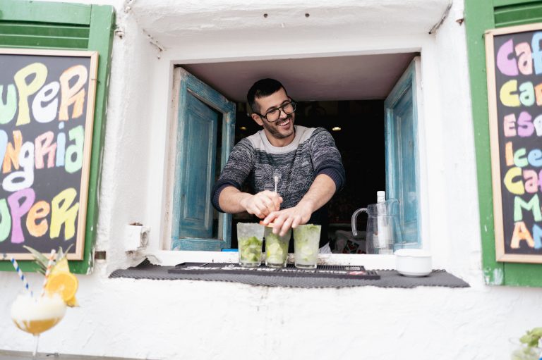 Man serving drinks from a colourful festival kiosk