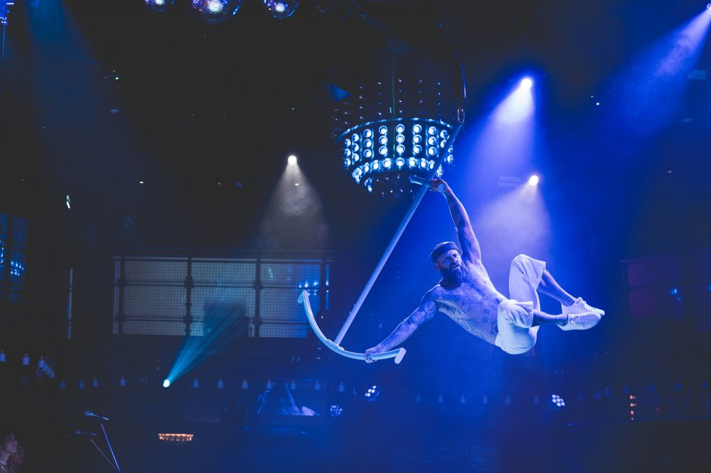 Aerial performer suspended in a blue spotlight
