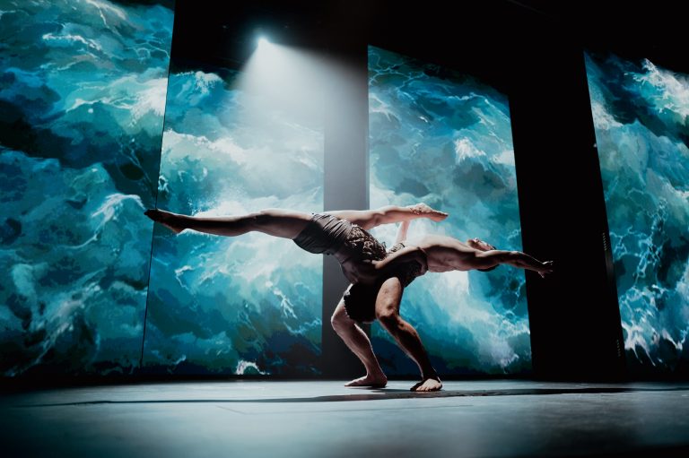 Dancer silhouetted against an underwater projection