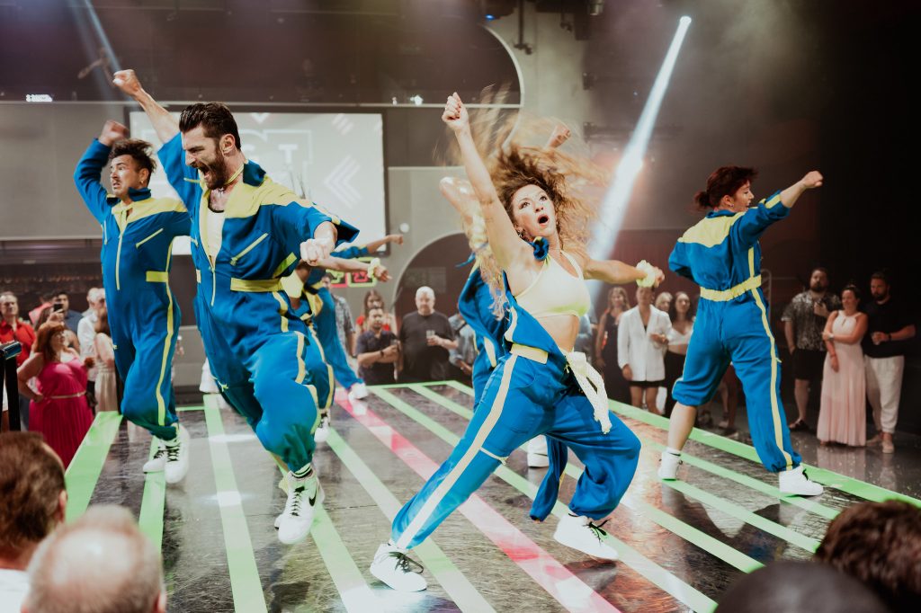 Ensemble performing a dance number in blue and white costumes