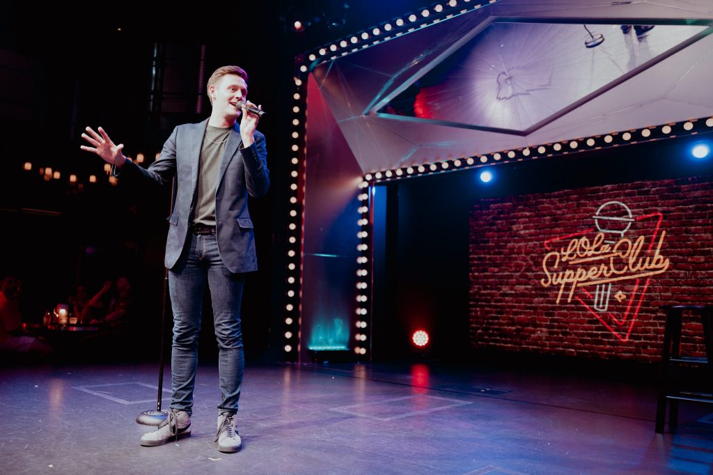Male performer addressing an audience from the stage