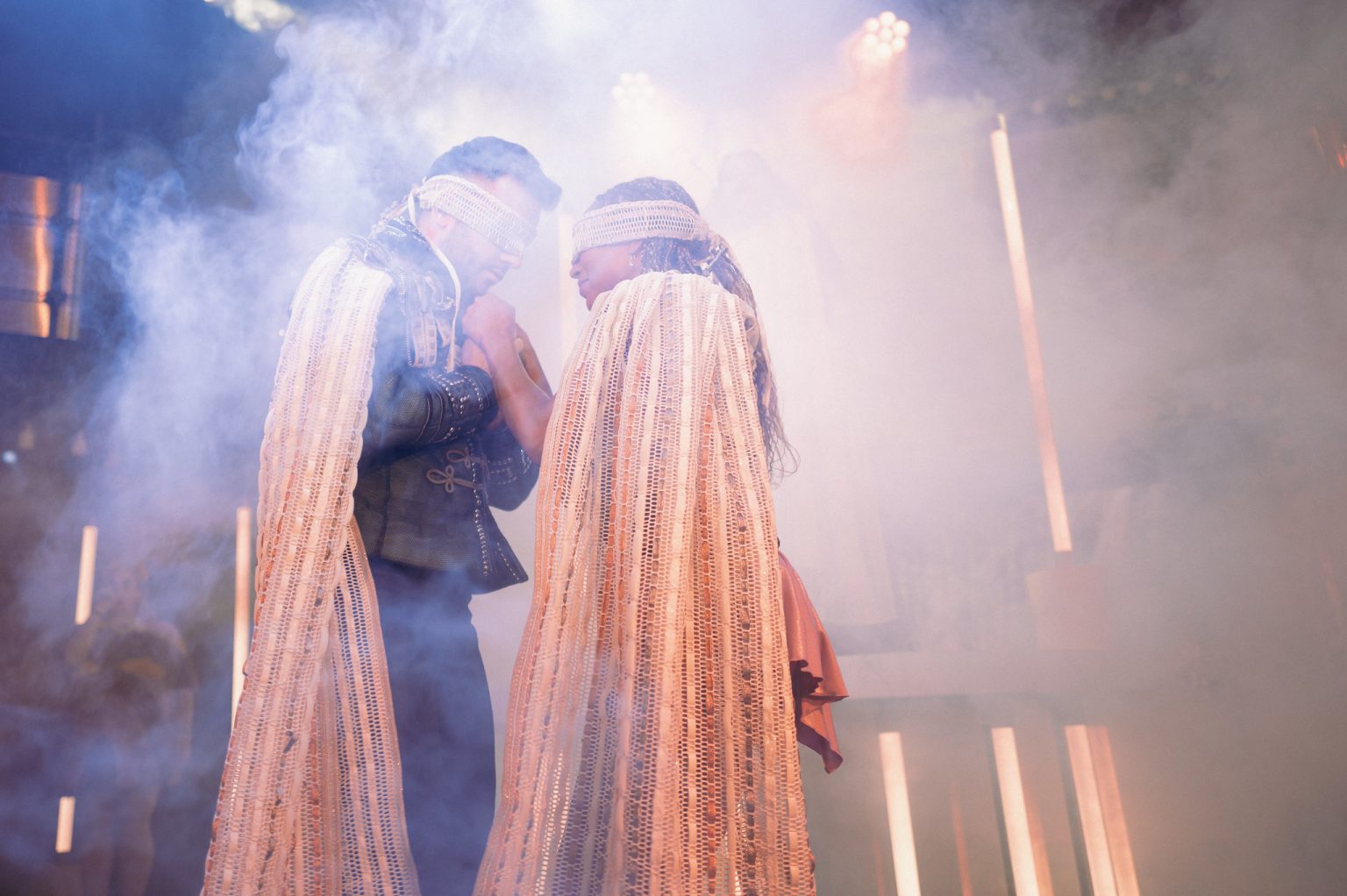 Two costumed performers emerging through stage smoke
