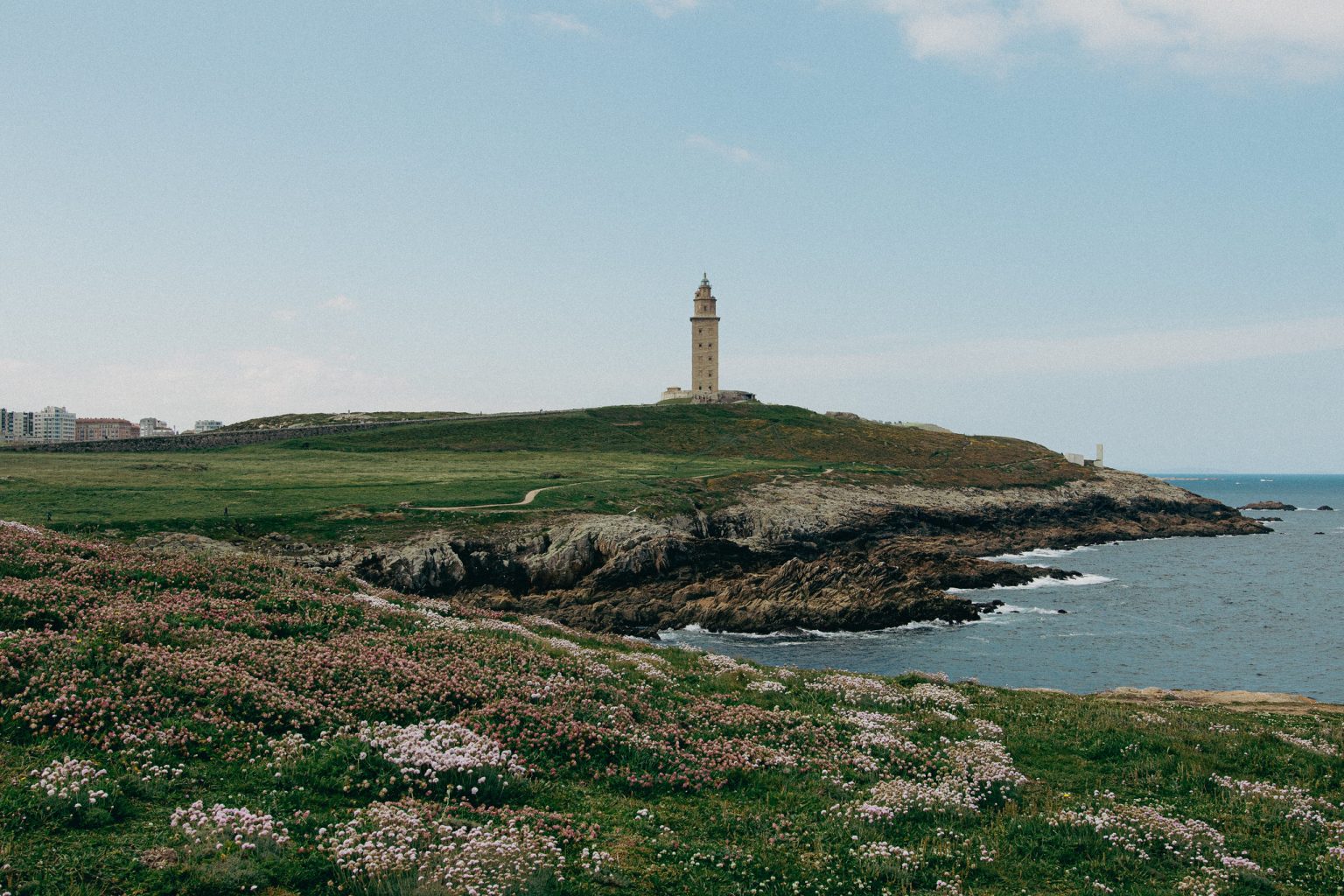 Lighthouse on a low rocky peninsula beneath blue sky