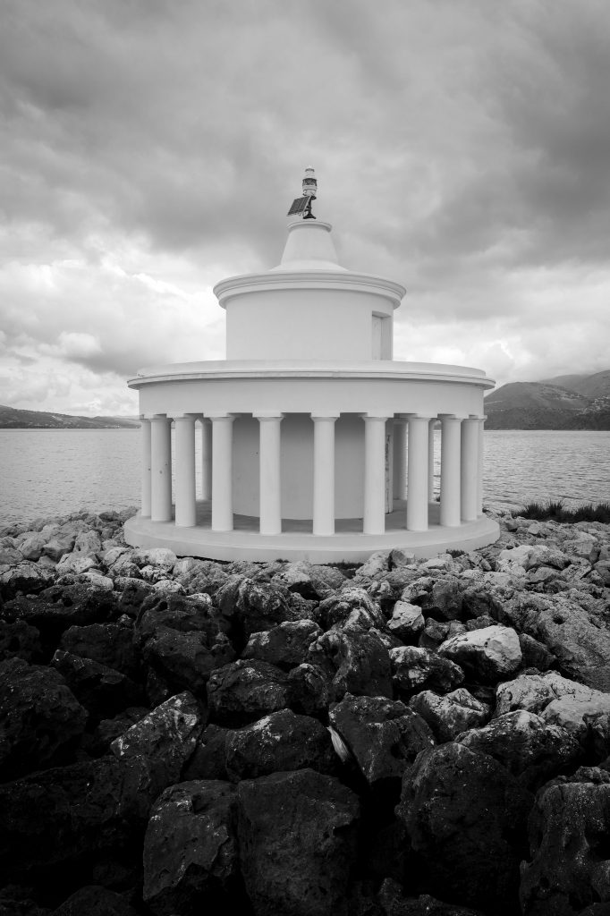 Black-and-white lighthouse beyond a rocky shoreline