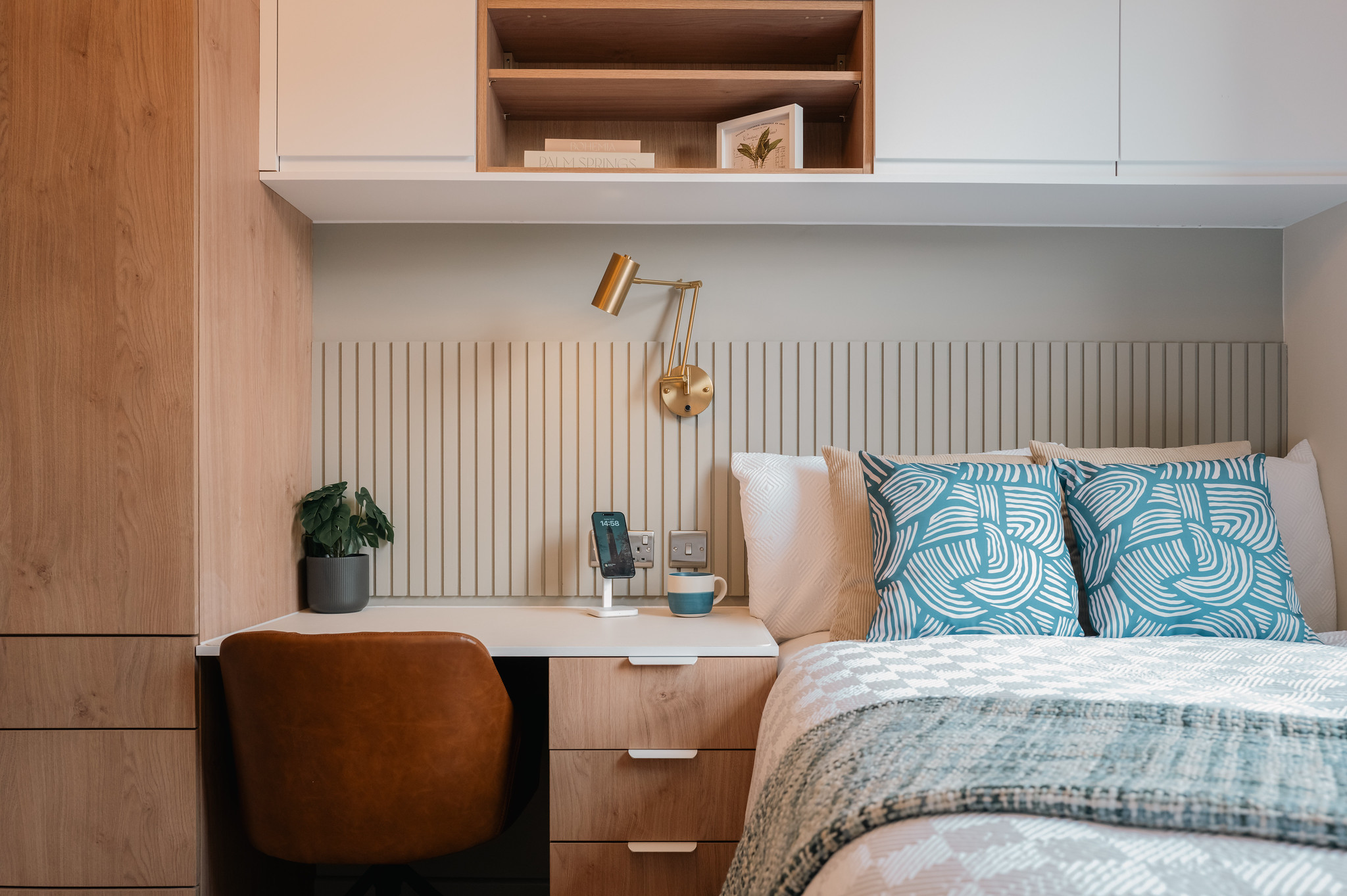 Compact bedroom with built-in desk and warm wood cabinetry