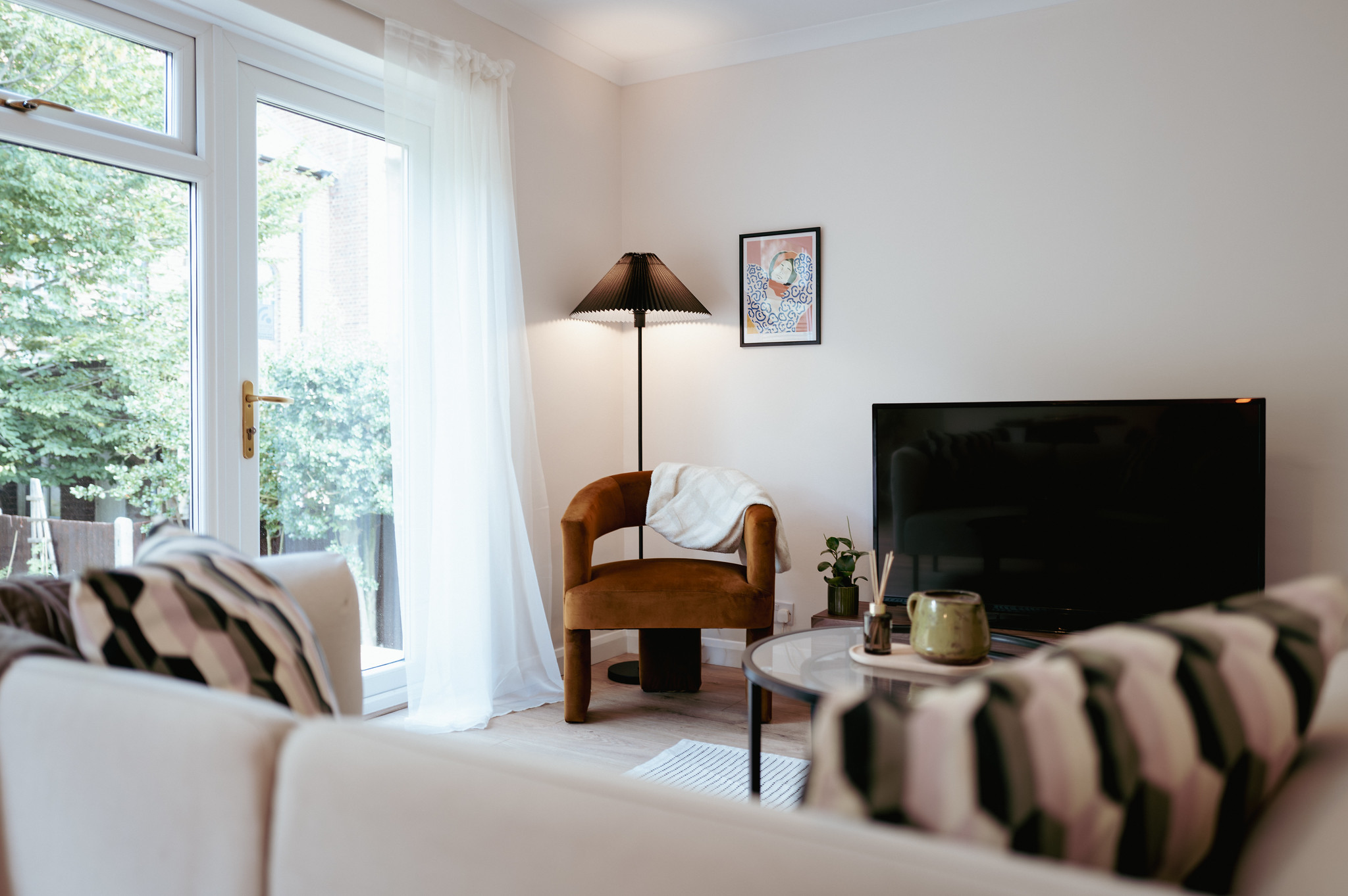 Naturally lit living room with garden doors and a brown armchair