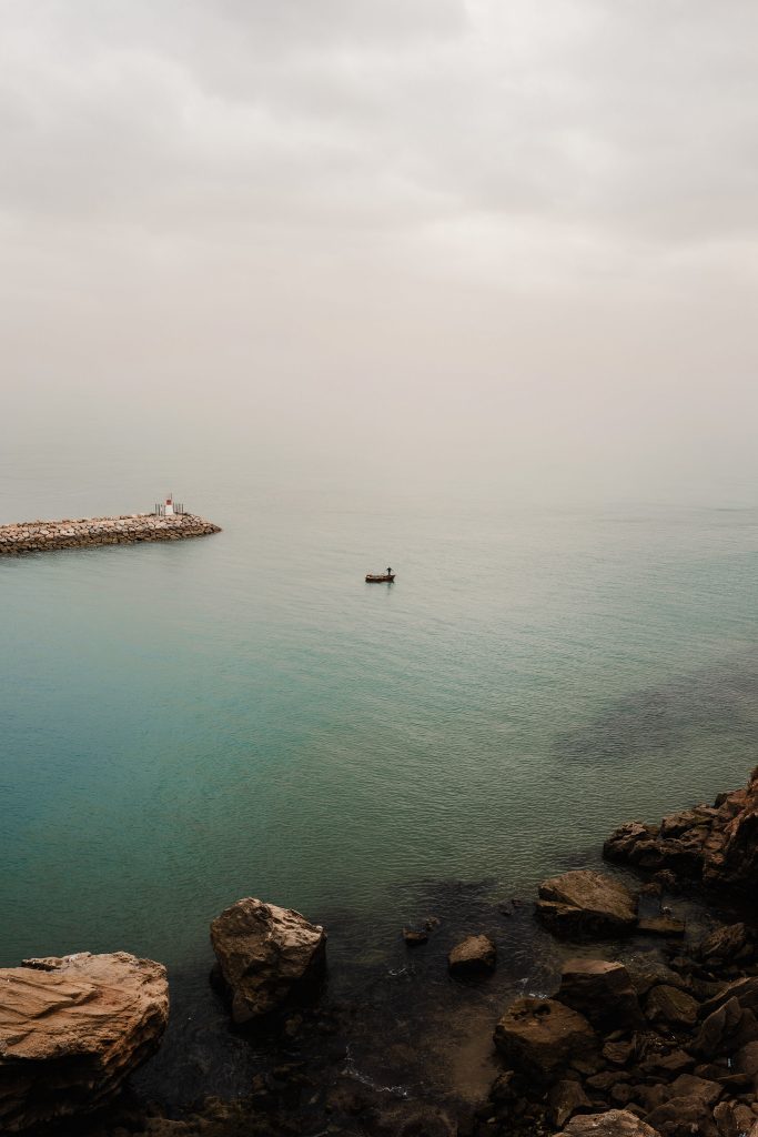 Small boat crossing a calm, hazy sea