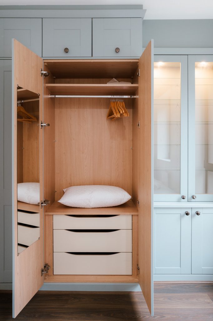 Open fitted wardrobe with wooden interior and pale blue cabinetry