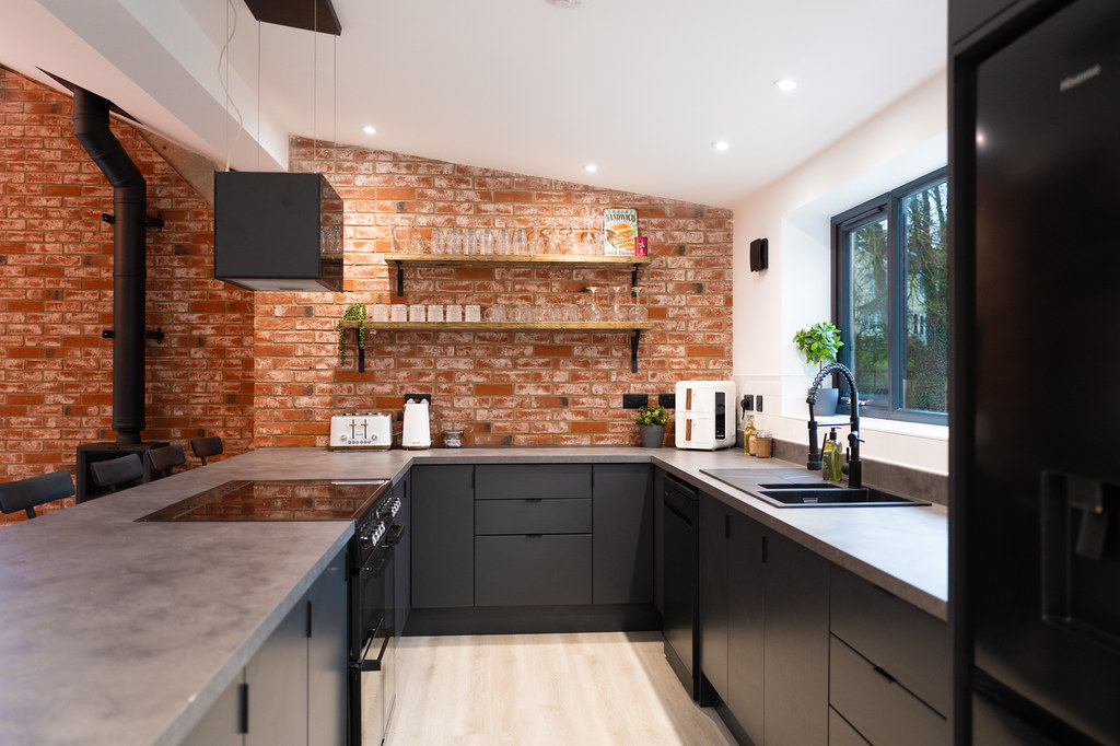Dark kitchen with exposed brick walls and concrete worktops