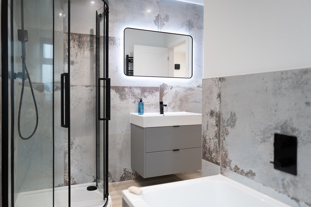 Bathroom with a walk-in shower, bath and concrete-effect walls