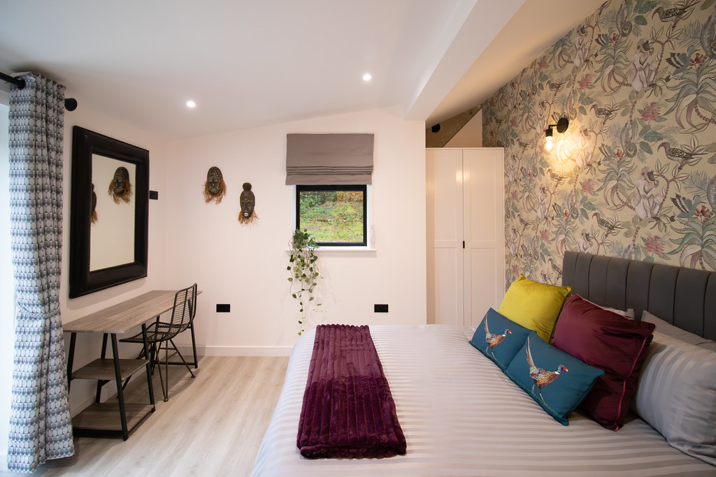 Bedroom with botanical wallpaper and colourful cushions