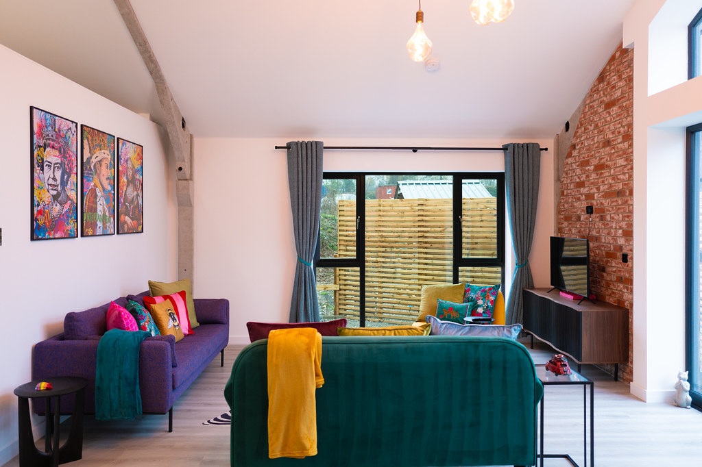 Colourful open-plan bedroom and living area with exposed brick