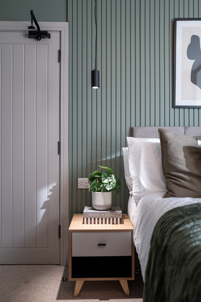 Bedside area with sage panelling and a small table