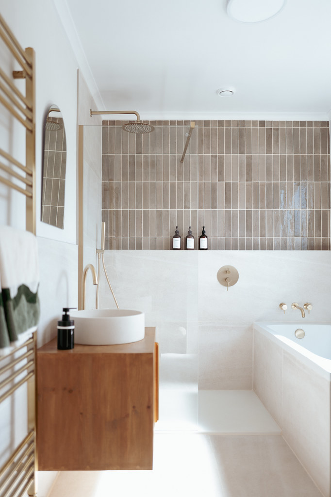 Bright bathroom with a tiled bath and wooden vanity