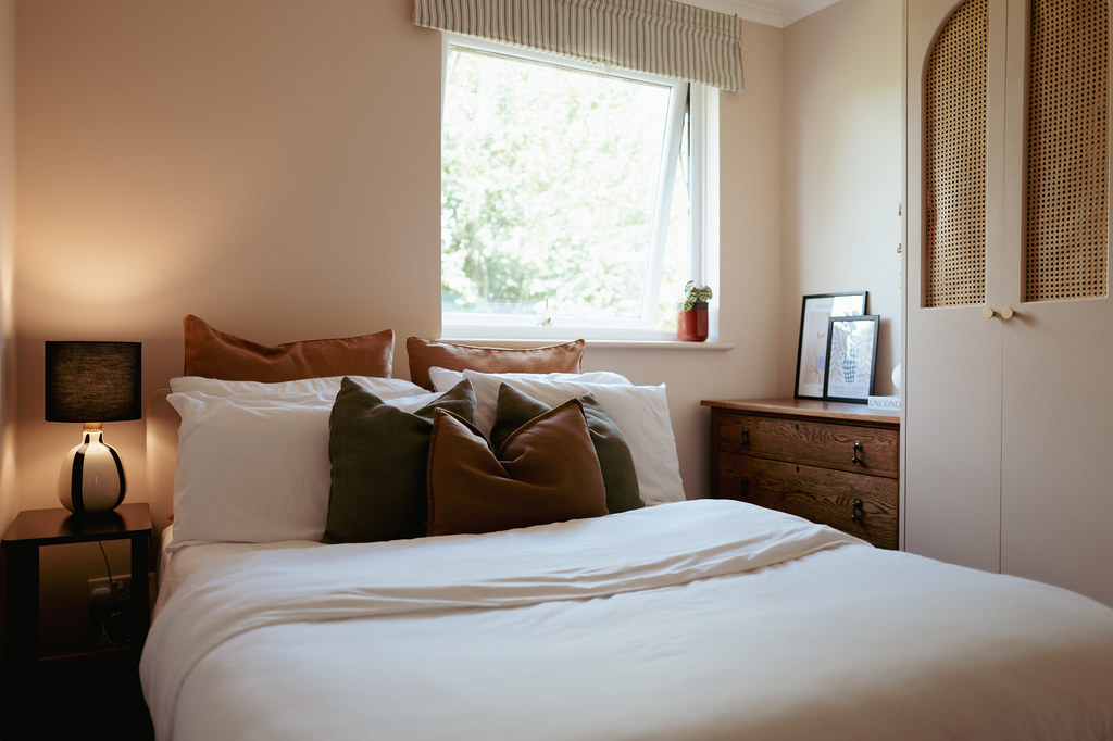 Warm neutral bedroom with wooden furniture and garden view