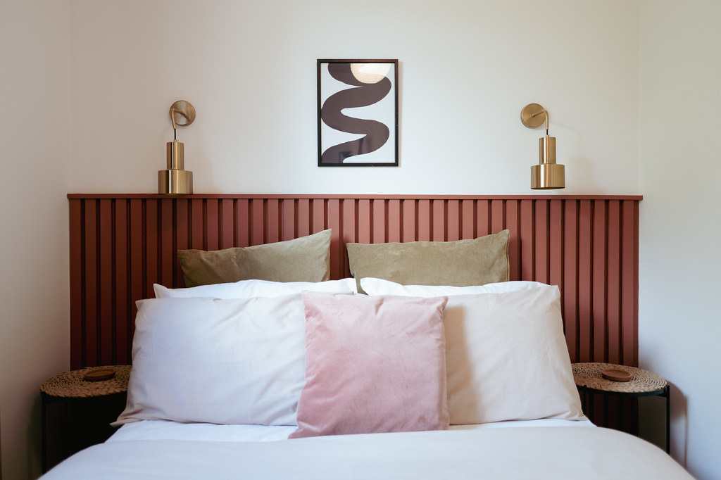 Guest bedroom with a slatted red headboard and pink cushions