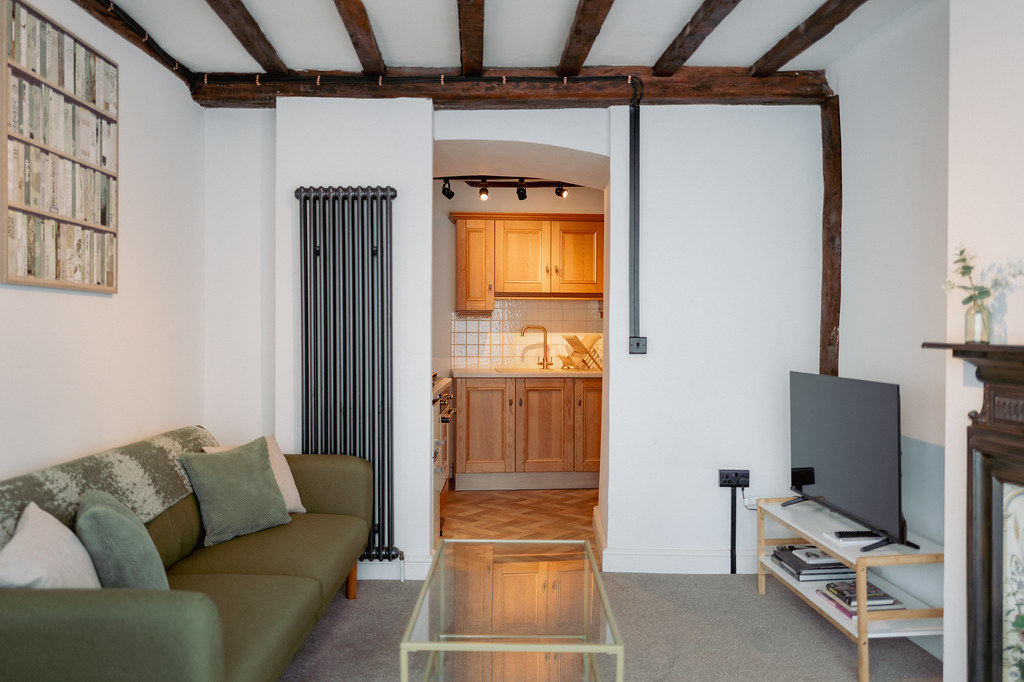 Living room with exposed beams and a doorway to the kitchen