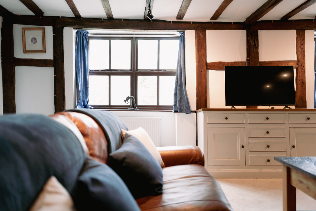 Living room with timber beams, leather sofa and sash window