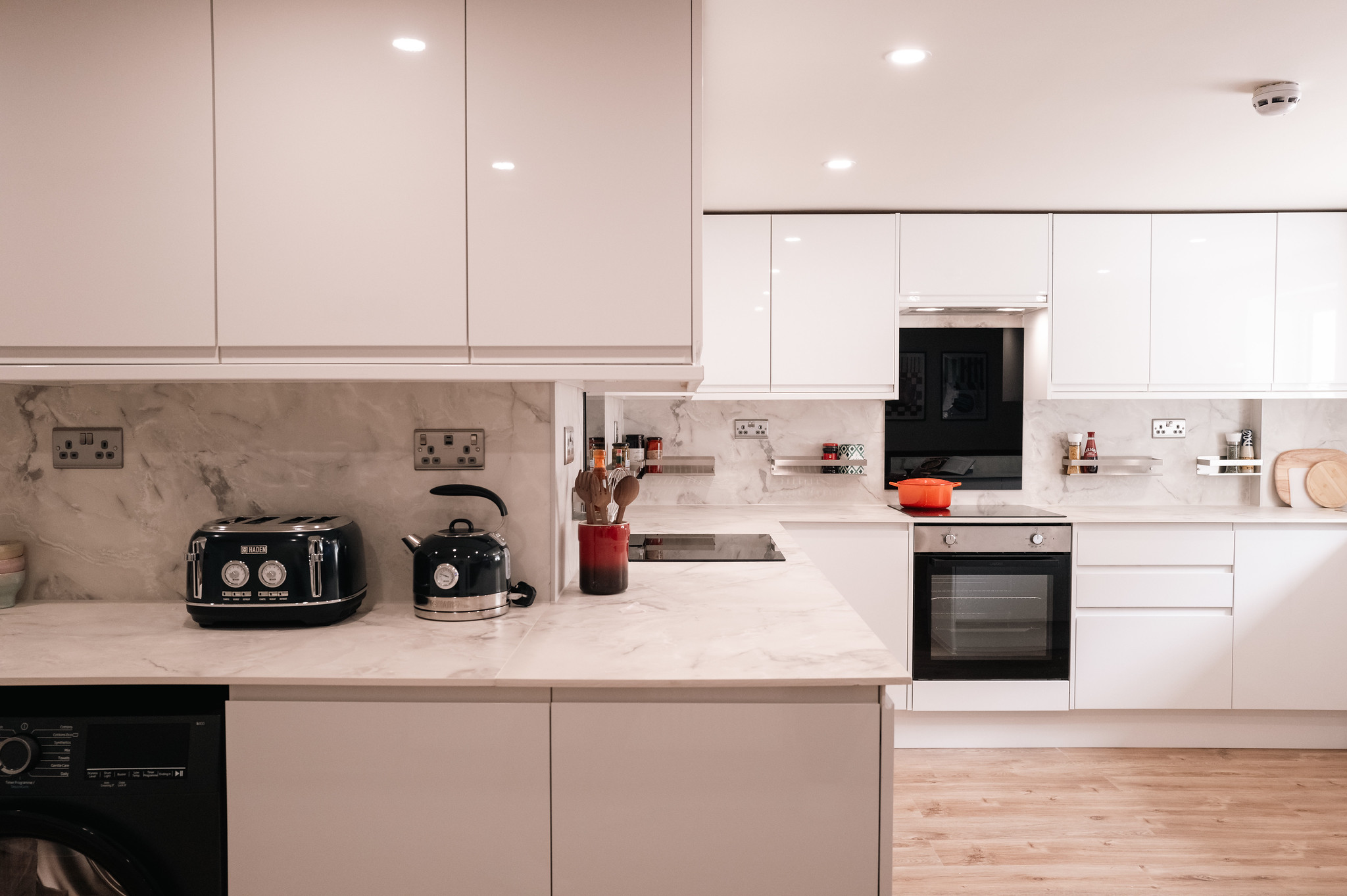 White shared kitchen with marble-effect worktops and black appliances