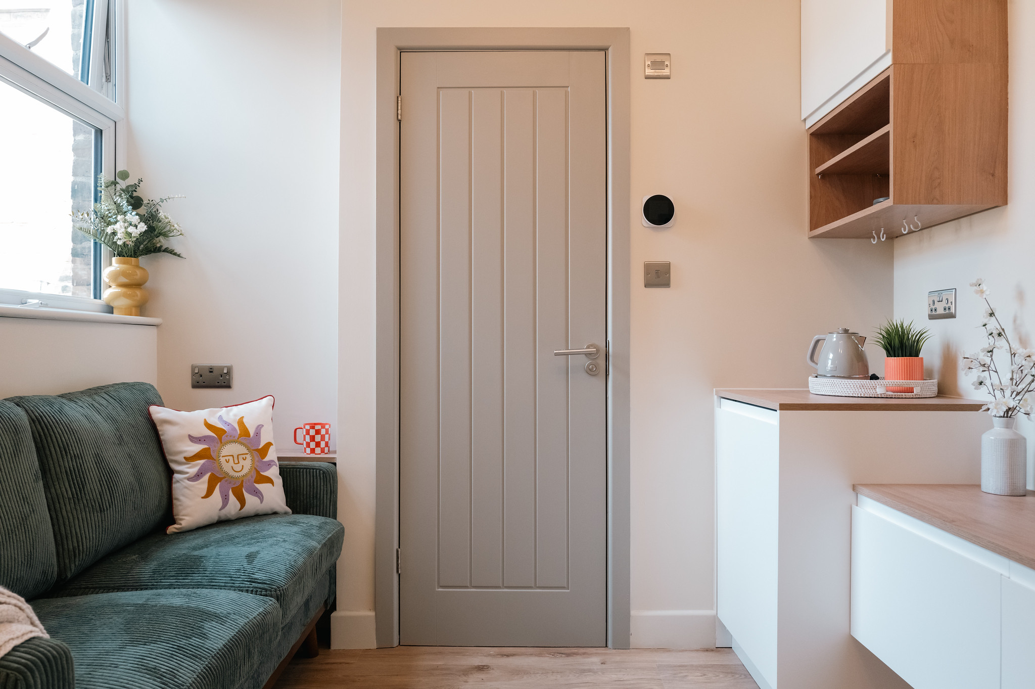 Compact room with green sofa, refreshment station and built-in storage